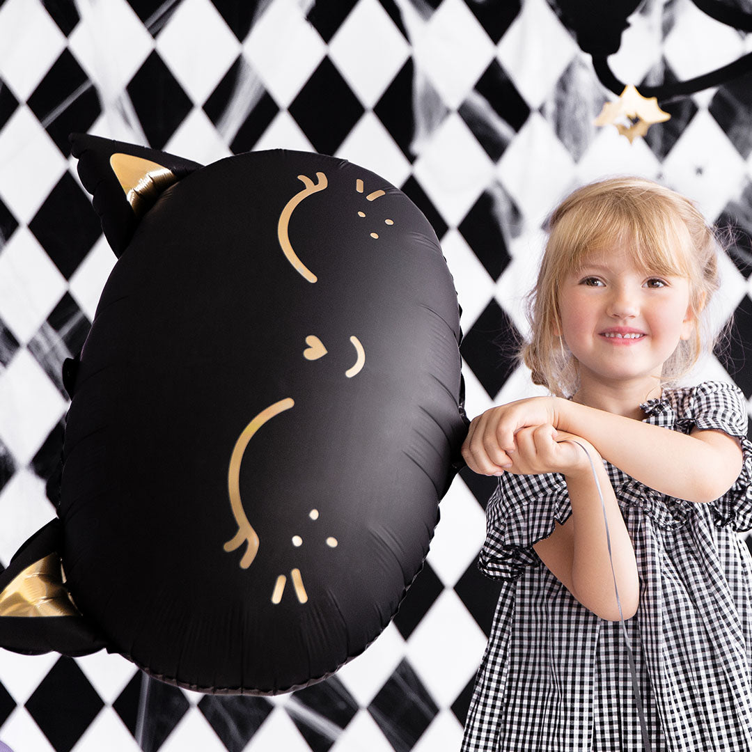 Een lachend meisje staat naast de partydeco zwarte kattenballon.