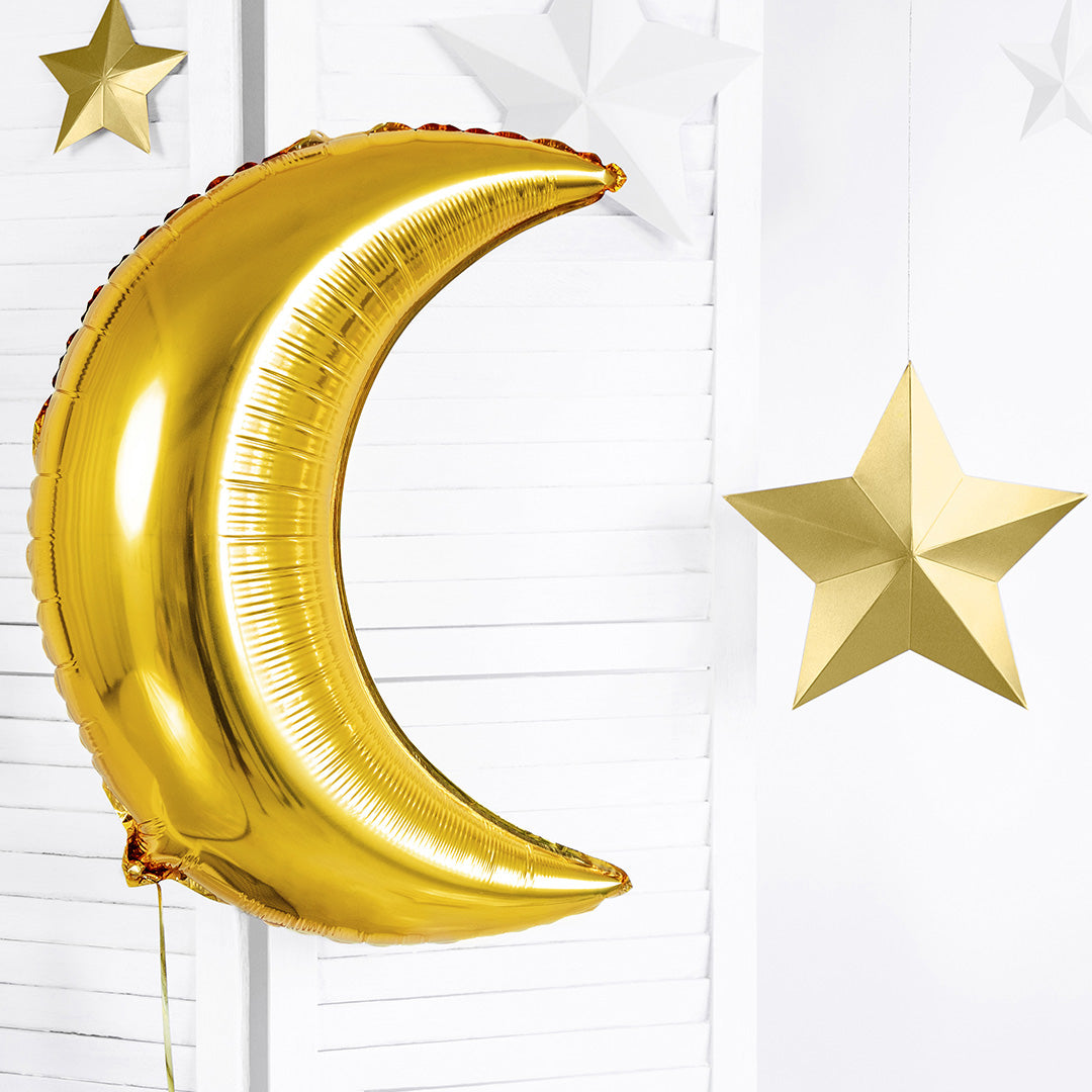 Partydeco gouden maan folieballon hangend aan een witte muur met gouden sterren.