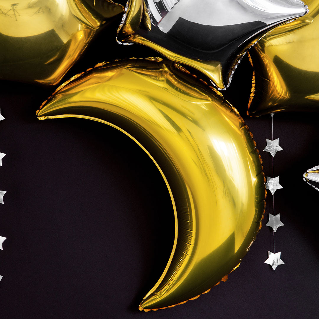 Partydeco gouden maan folieballon tussen andere feestdecoratie met sterren.