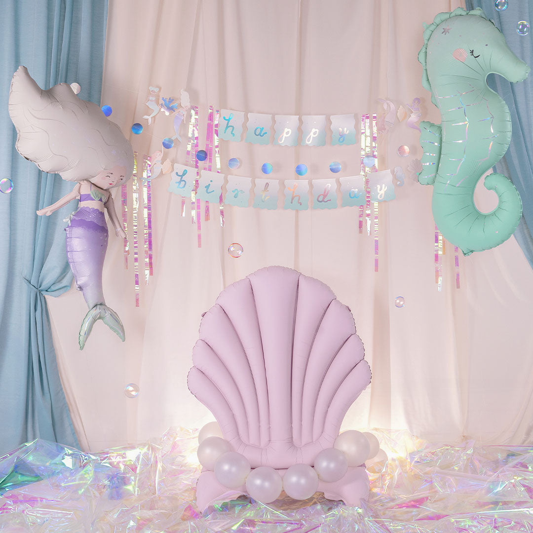 Partydeco roze schelp folieballon gebruikt als stoel in een onderwater thema feestdecoratie.