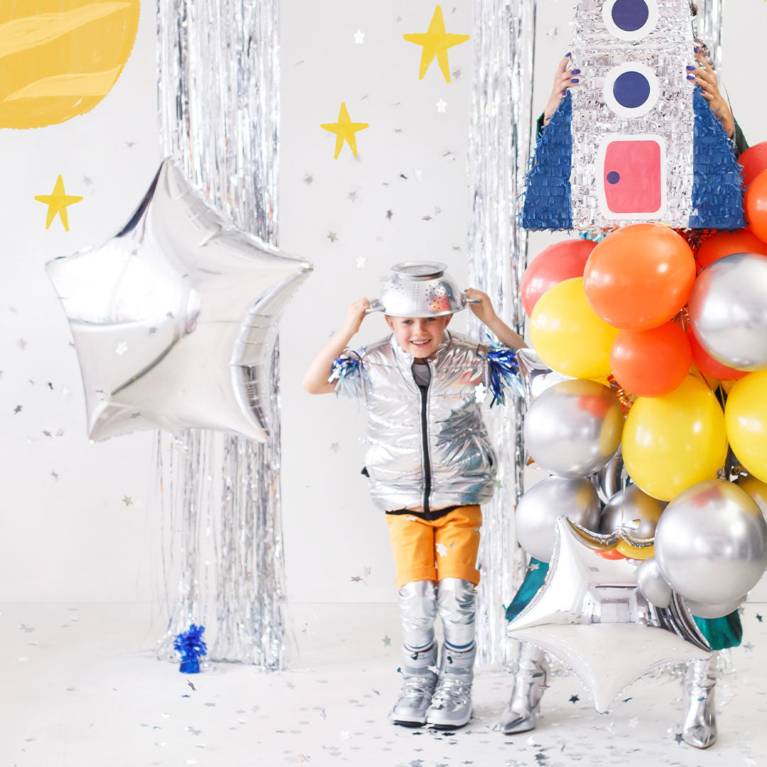 Een kind in ruimtepak met een Partydeco zilveren ster folieballon en andere feestballonnen.