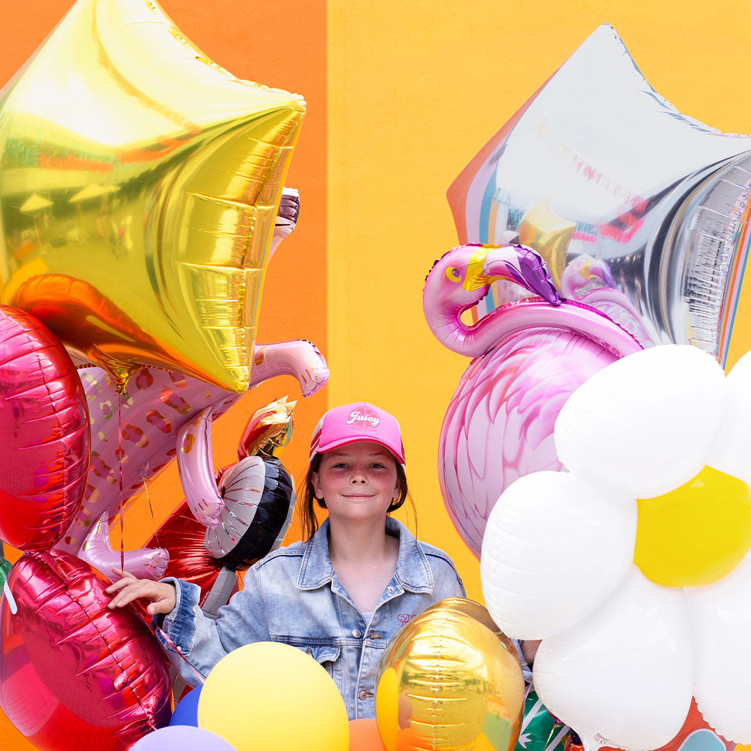 Een meisje tussen diverse feestballonnen, waaronder een Partydeco zilveren ster folieballon.