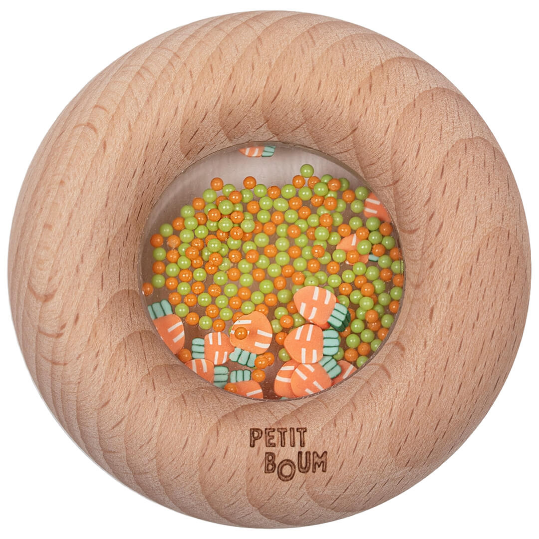Petit Boum houten bijtring en rammelaar met wortelthema, gevuld met oranje en groene kraaltjes en wortelconfetti.