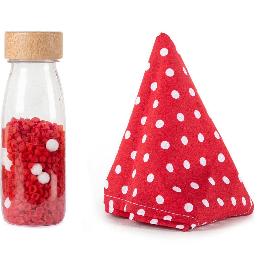 Petit Boum sensorische fles met rode en witte korrels en een rood stippendoekje.