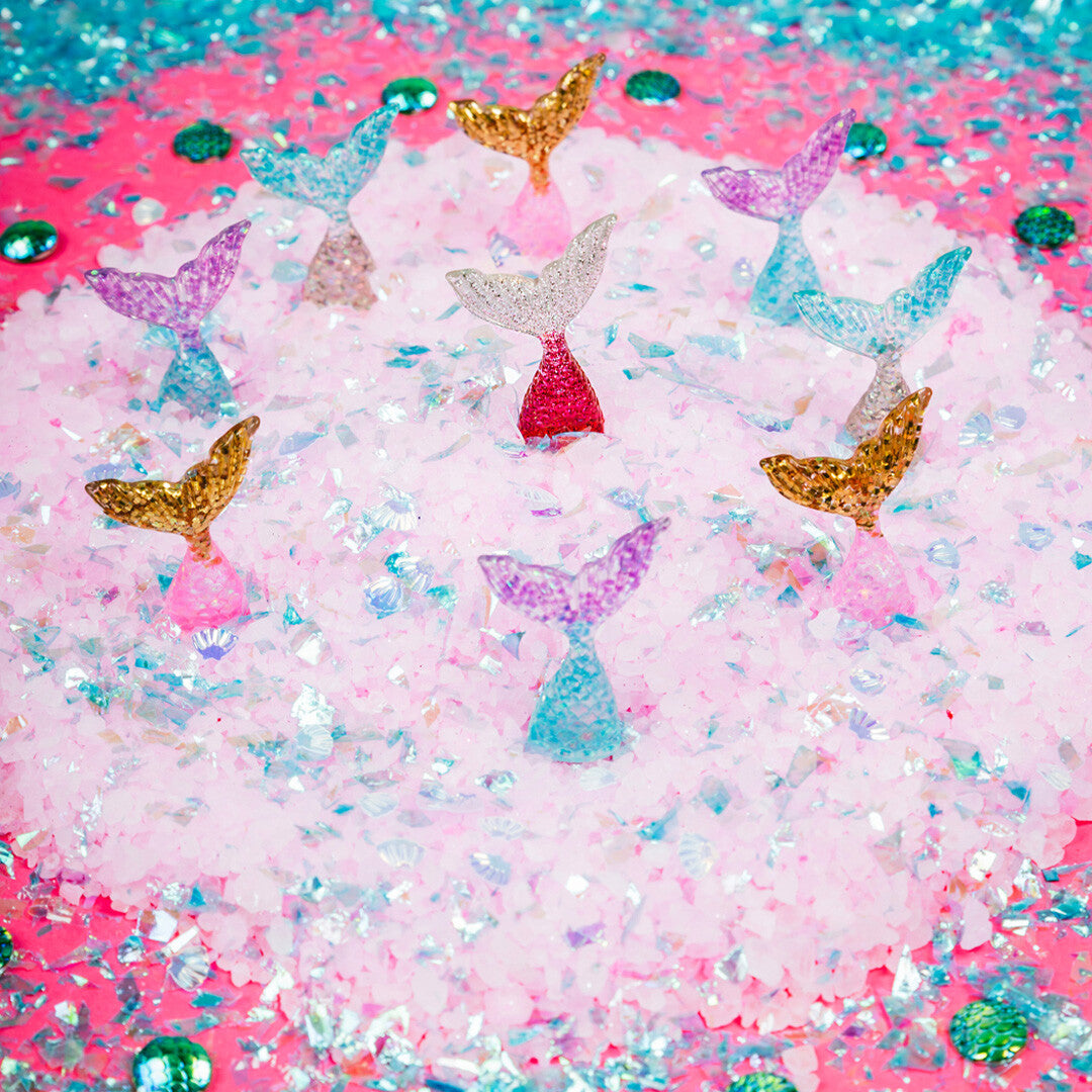 Detail van meerdere kleurrijke zeemeerminstaartjes in een berg roze en iriserende glitters.