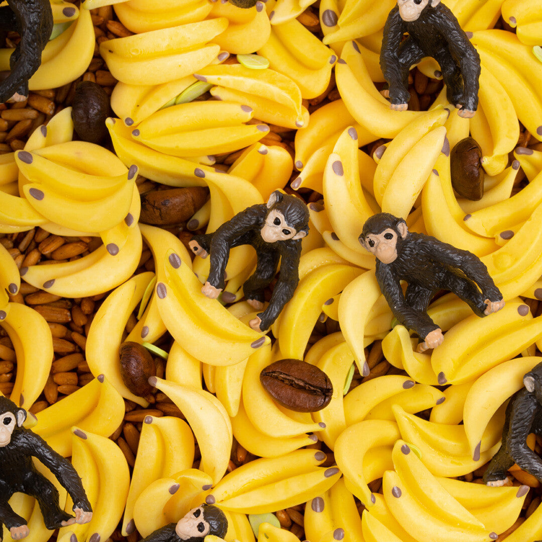 Detailfoto van kleine gele bananen, koffiebonen en aapjes tussen graankorrels.