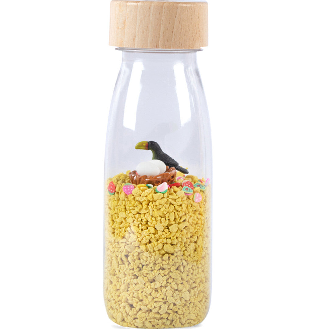 Petit boum sensorische fles met een toekan, nest en eieren op gele korrels.