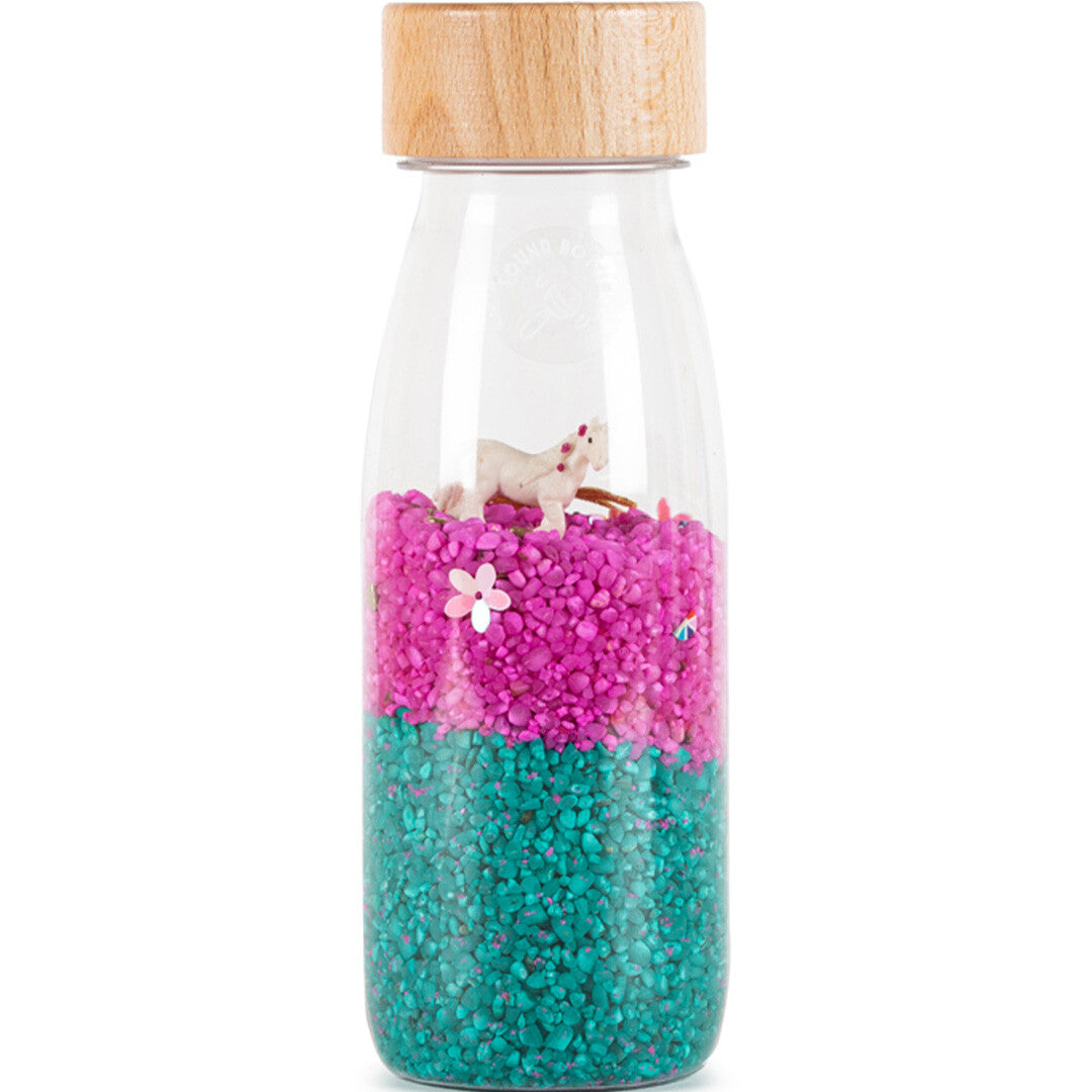 petit boum sensorische fles met roze en turquoise steentjes, een wit eenhoornfiguur en een houten dop.