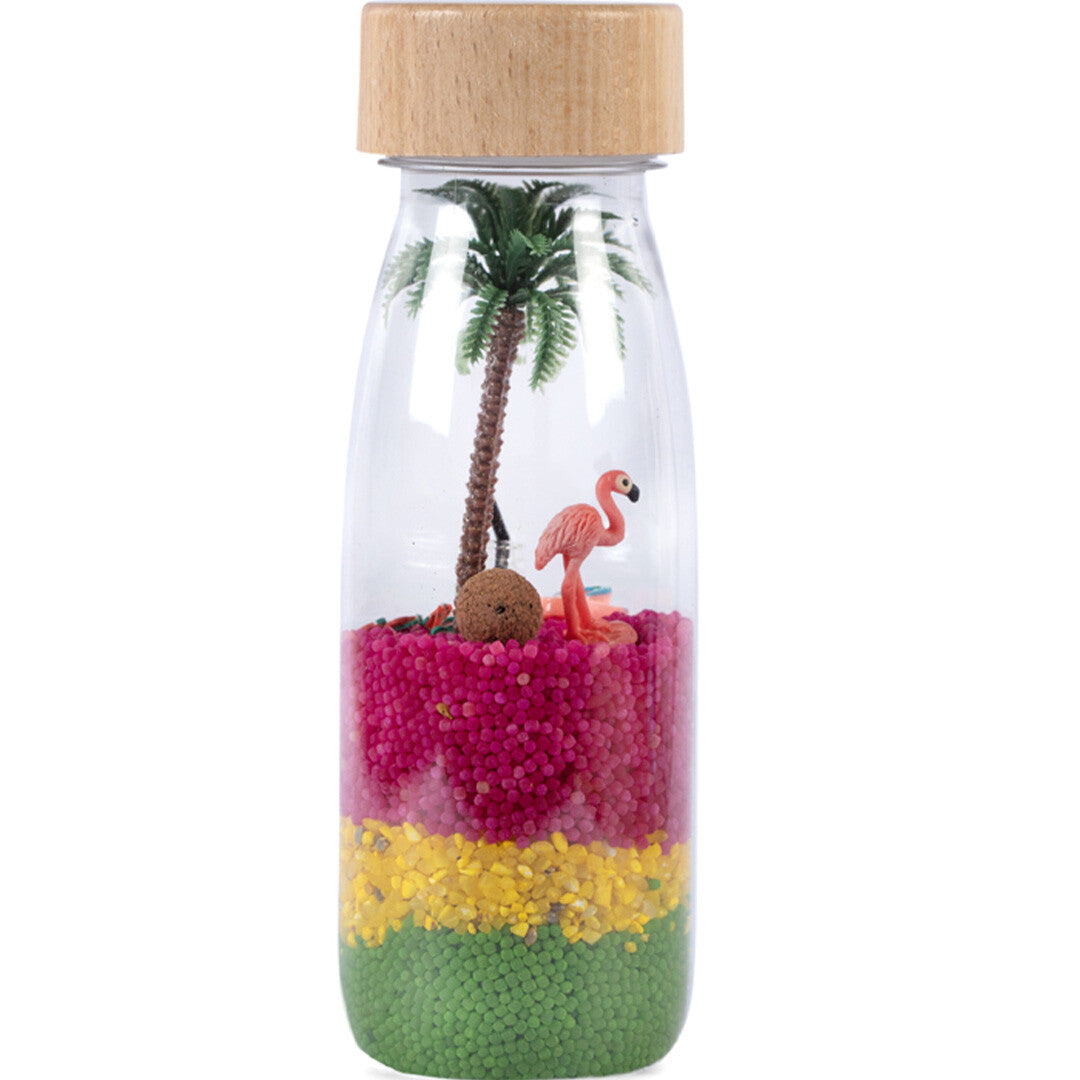Petit boum sensorische fles met een tropisch flamingo thema, gevuld met gekleurde kralen, een palmboom en een flamingo.
