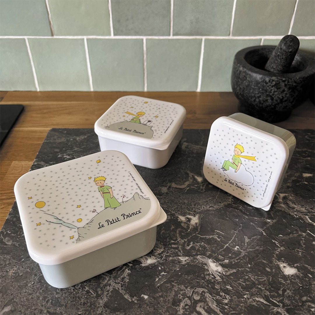 Drie Petit Jour snackdoosjes met de Kleine Prins op een aanrecht.