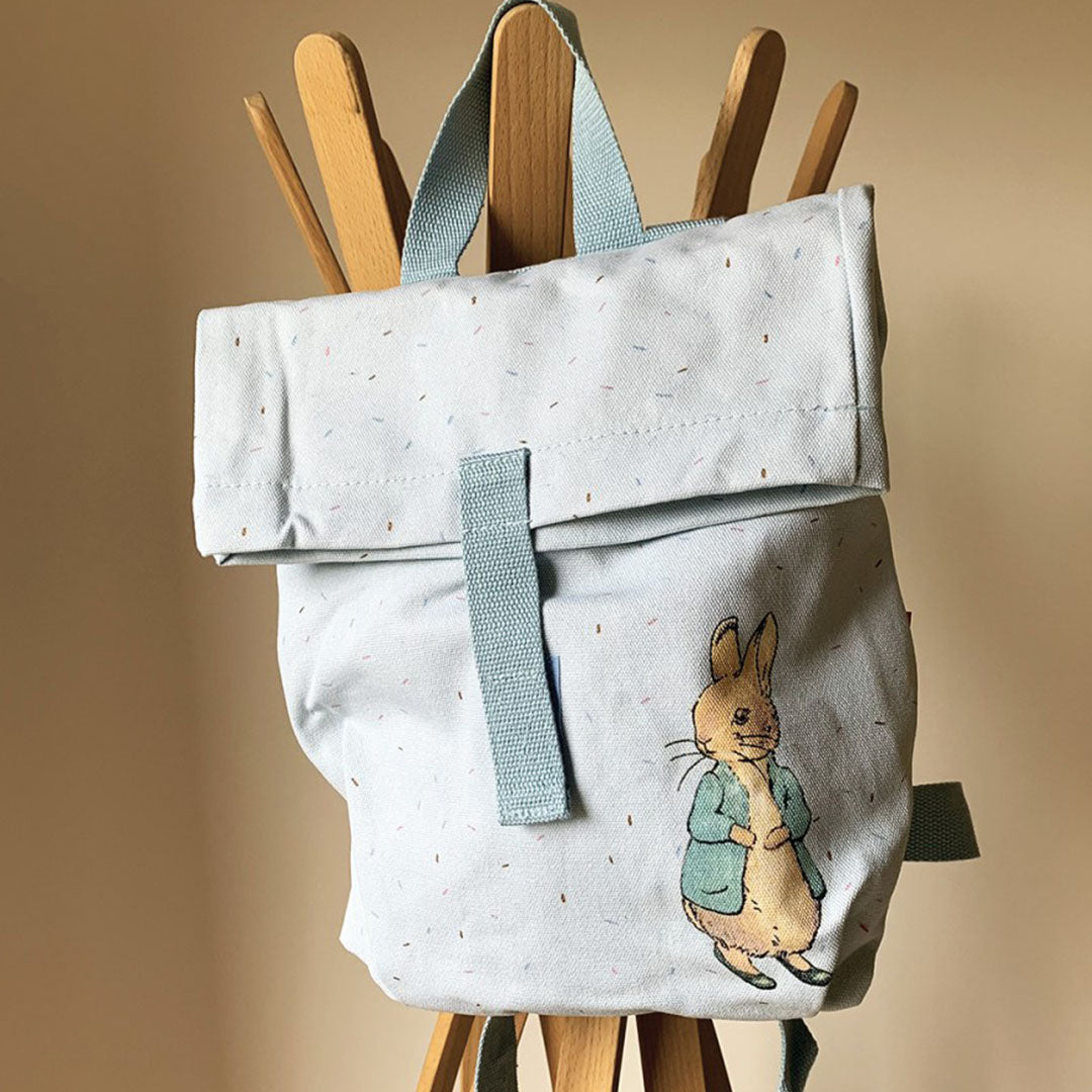 Lichtblauwe kinderrugzak met Pieter Konijn hangend aan een houten kapstok.