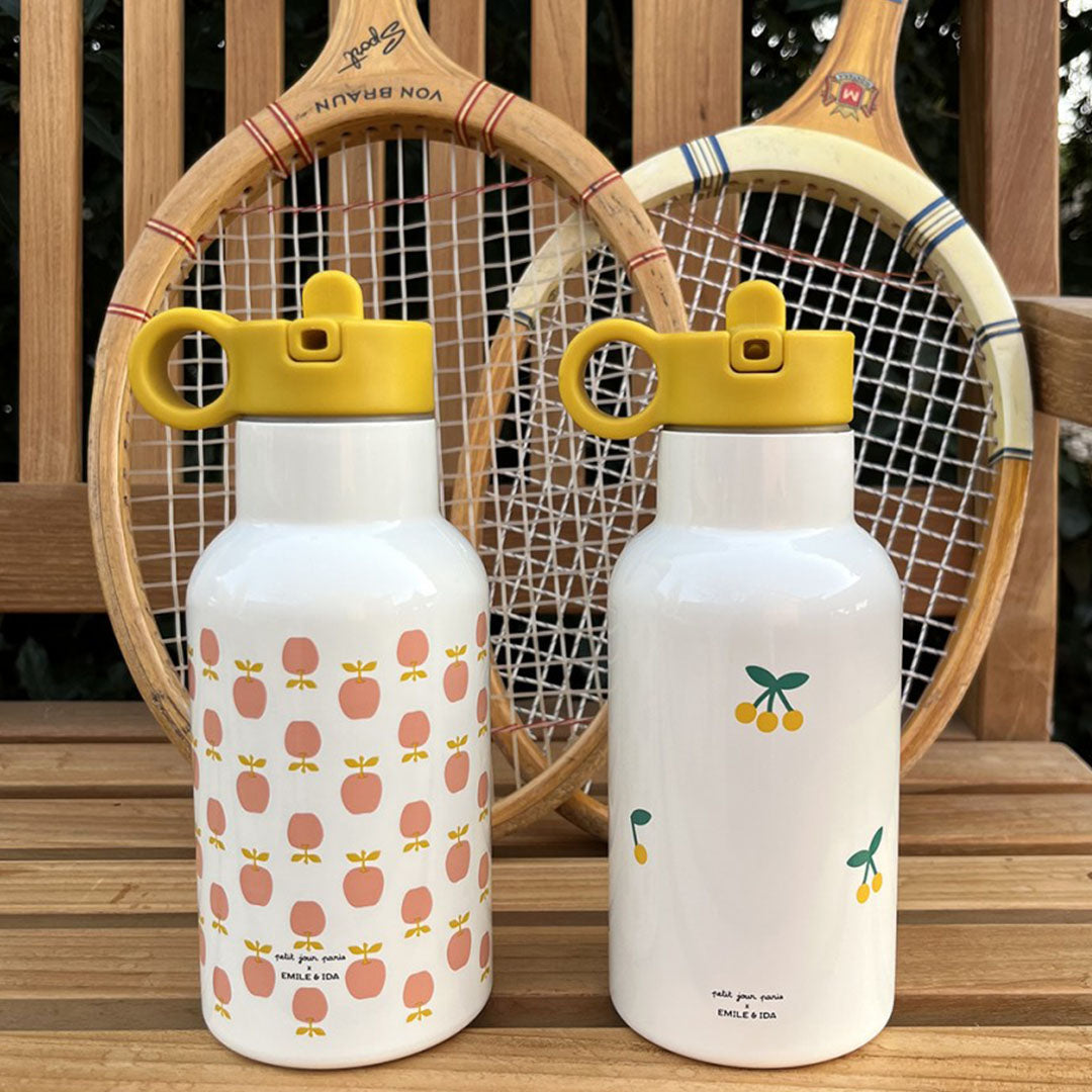 Twee petit jour rvs drinkflessen, één met kersen en één met appels, op een houten bankje.
