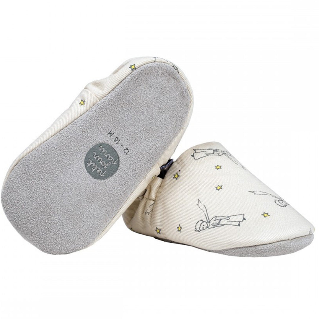 Twee petit jour baby schoentjes met zachte zool, beige met een patroon van De Kleine Prins en sterren, waarbij de onderkant met maatlabel zichtbaar is.