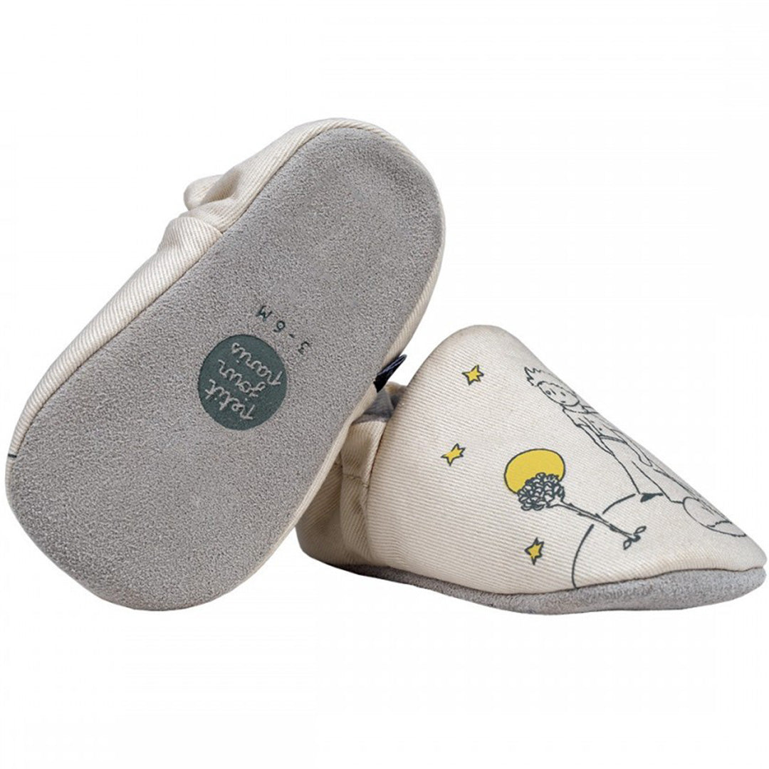 De onderkant van een beige petit jour baby schoentje met zachte zool en maatindicatie, naast een schoentje met De Kleine Prins illustratie.