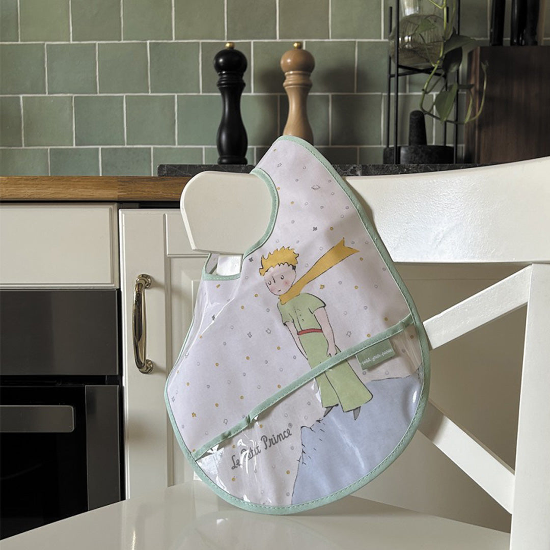 Petit Jour slabbetje met De Kleine Prins hangend over een witte stoel in een keuken.