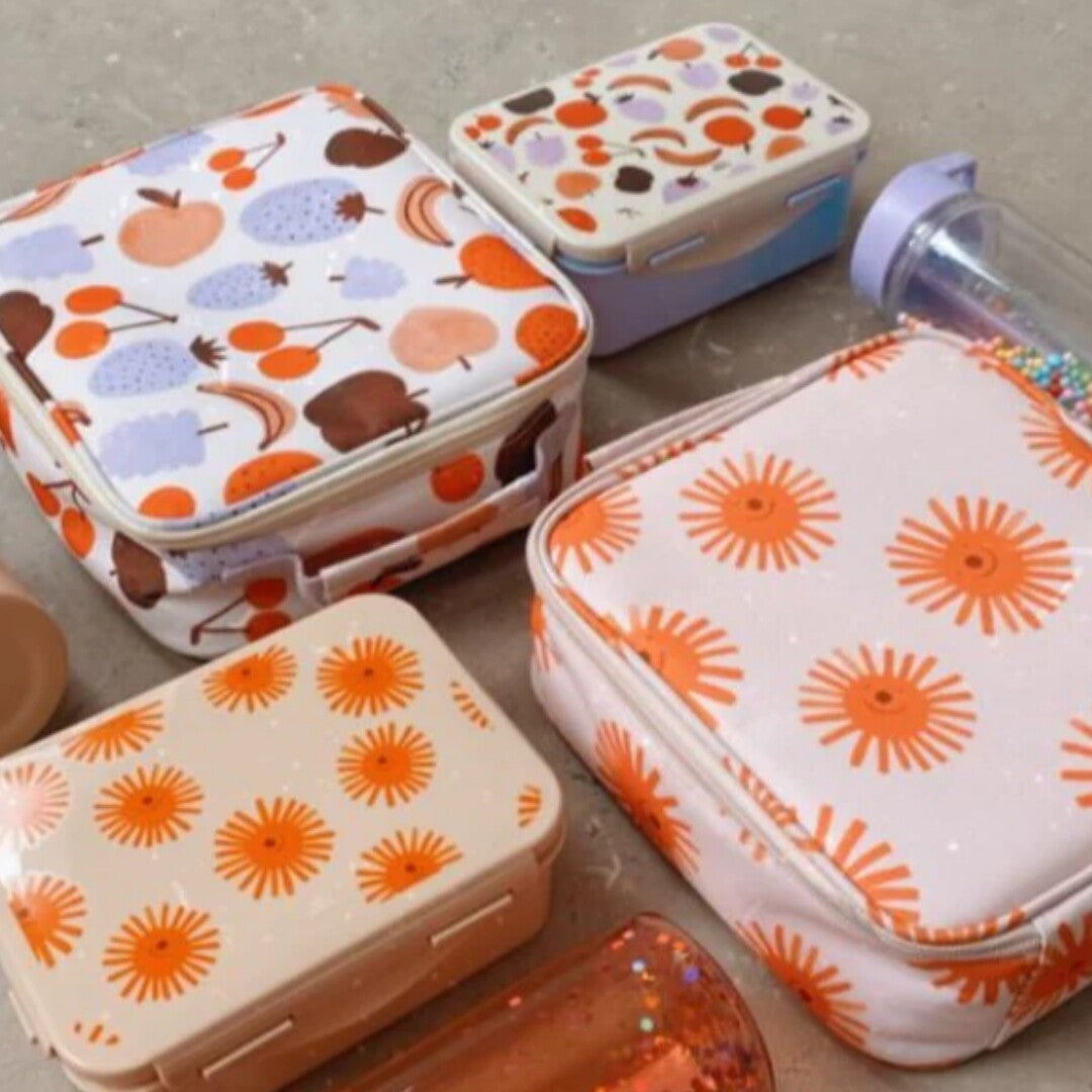 Collectie Petit Monkey lunchproducten, waaronder broodtrommels en lunchtassen met fruit- en zonnepatronen.