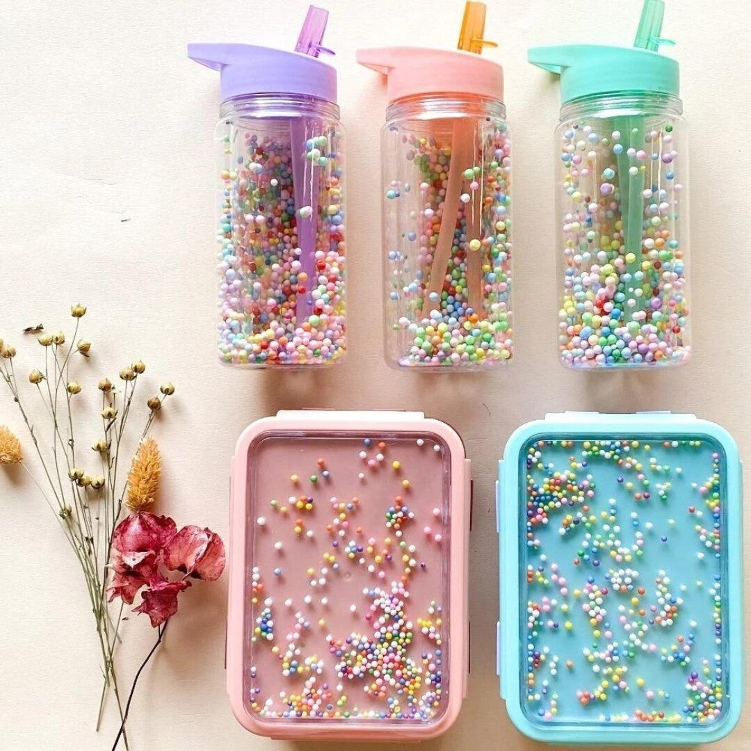 Drie Petit Monkey kinder drinkflessen en twee lunchboxen met kleurrijke macaron pops.
