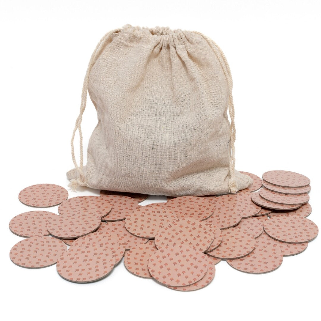 Een beige stoffen zak met trekkoord en verspreide ronde Petit Monkey memo game kaarten met een patroon op de achterzijde.