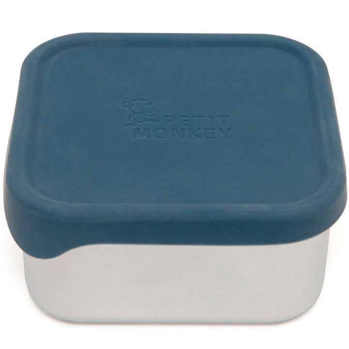 Petit Monkey RVS snackdoosje met blauw siliconen deksel en logo, schuin van bovenaf gefotografeerd.
