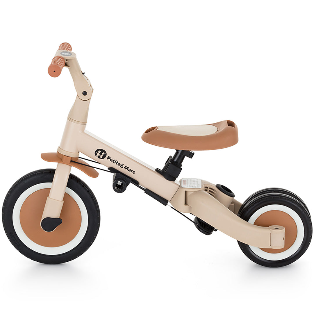 Petite&Mars 5-in-1 kinderfiets in desert sand kleur, geconfigureerd als loopfiets met twee achterwielen, van links gezien.