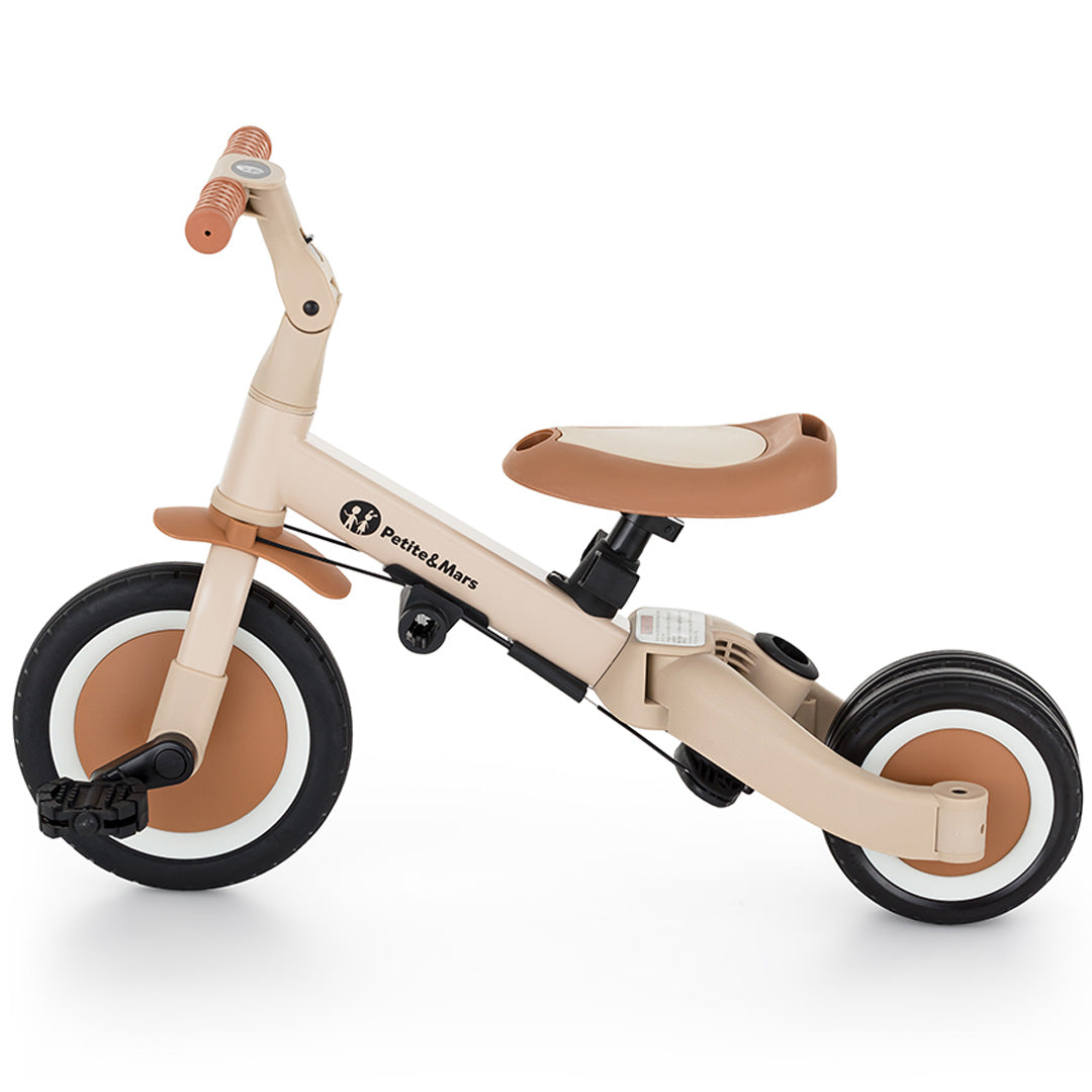 Petite&Mars 5-in-1 kinderfiets in desert sand kleur, geconfigureerd als loopfiets met pedalen en twee achterwielen, van links gezien.