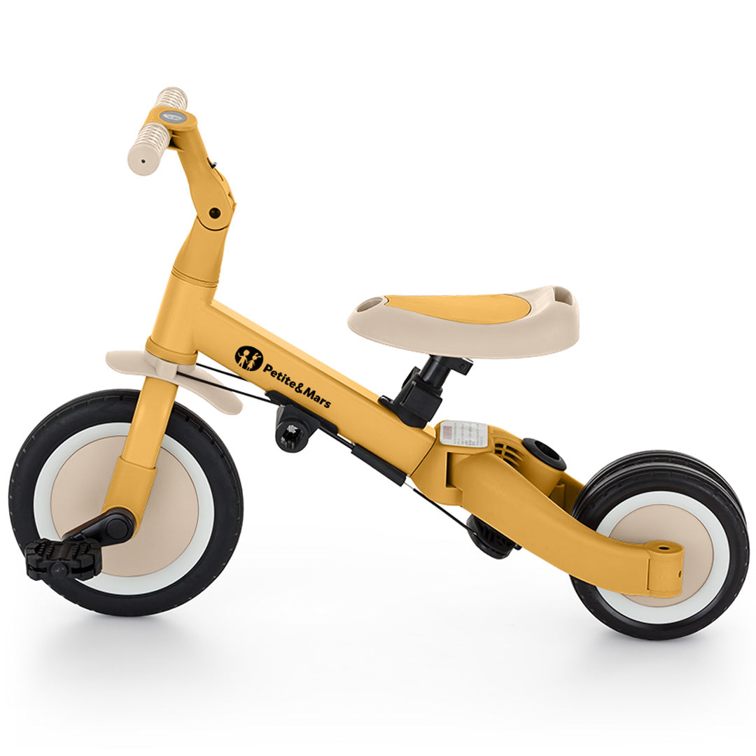 Petite&Mars 5-in-1 kinderfiets in intense ochre als loopfiets met twee achterwielen en pedalen ingeklapt, van de zijkant.