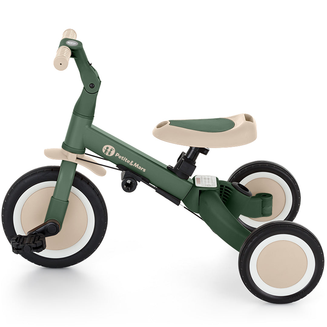 De groene Petite&Mars 5-in-1 kinderfiets in driewielerstand met pedalen.
