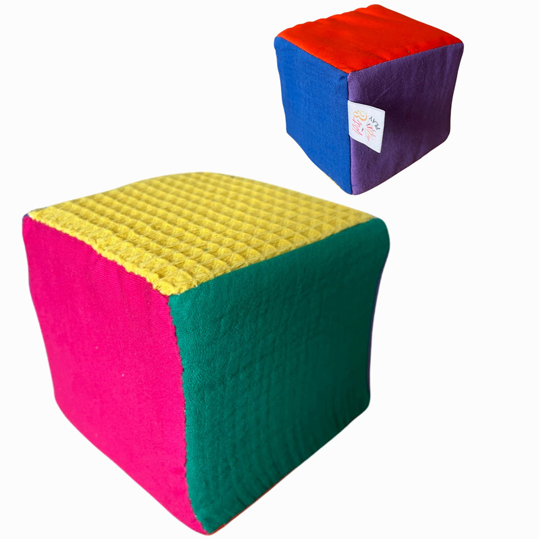Twee pit and play regenboog dobbelstenen van stof en schuim, met verschillende texturen.