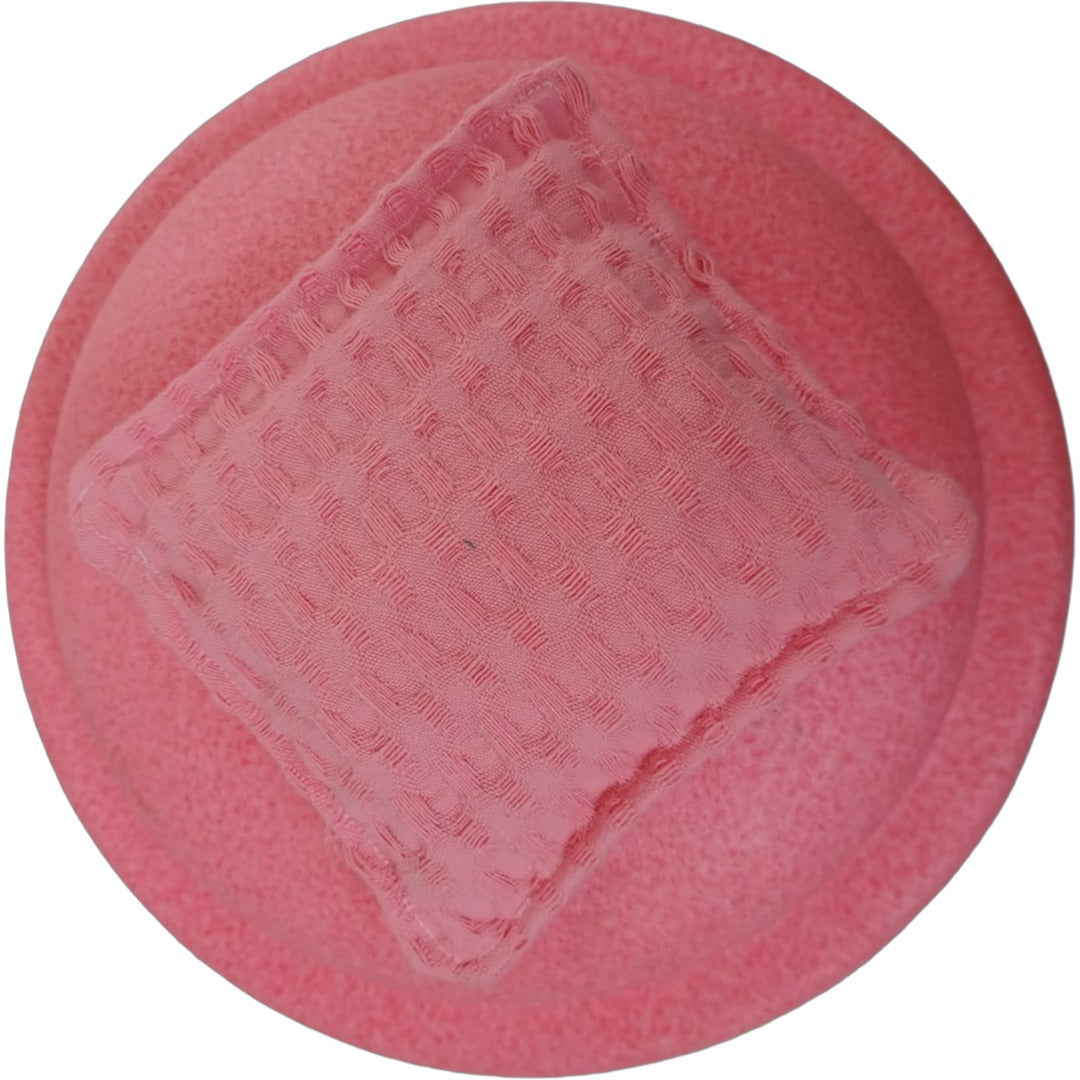 Bovenaanzicht van een pastelroze pit and play pittenzakje met textuur op een ronde roze ondergrond.