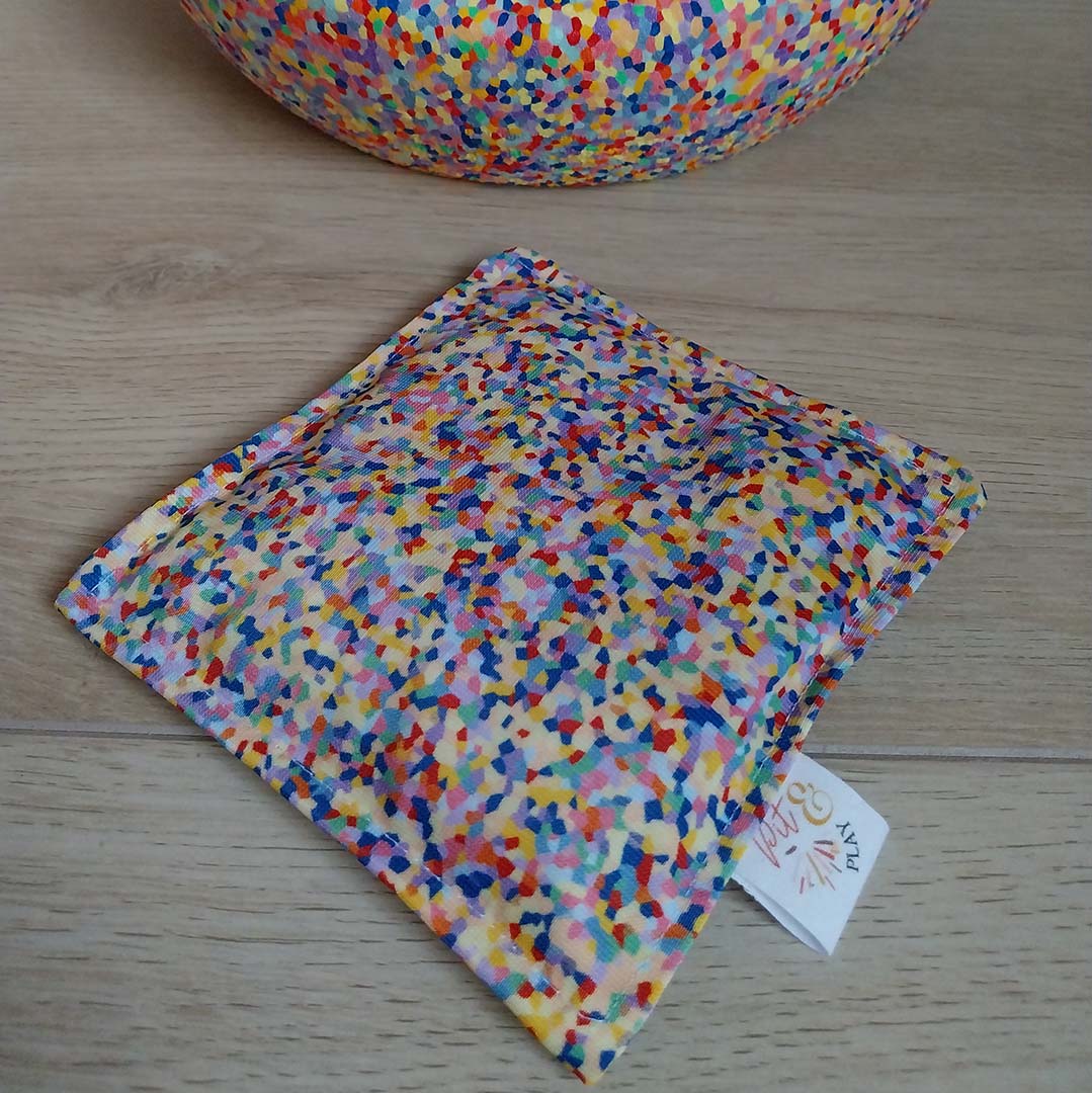 Pit & Play sensorisch pittenzakje met confetti patroon op een houten ondergrond, met een bijpassende kom op de achtergrond.
