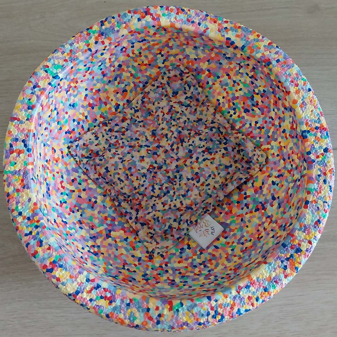 Bovenaanzicht van een Pit & Play sensorisch pittenzakje met confetti patroon, liggend in een bijpassende kom.