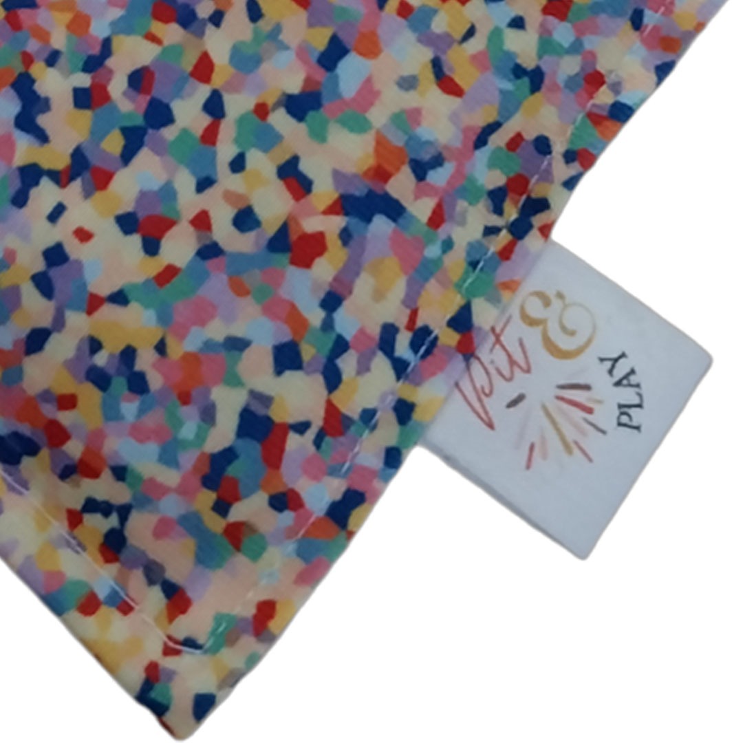 Detailopname van het kleurrijke confetti patroon en het Pit & Play merklabel op het sensorische pittenzakje.