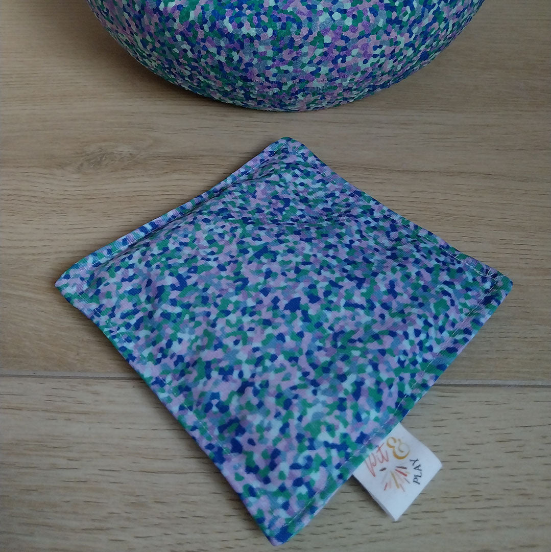 Pit and play pittenzakje met veelkleurig abstract stippenpatroon op een houten ondergrond.