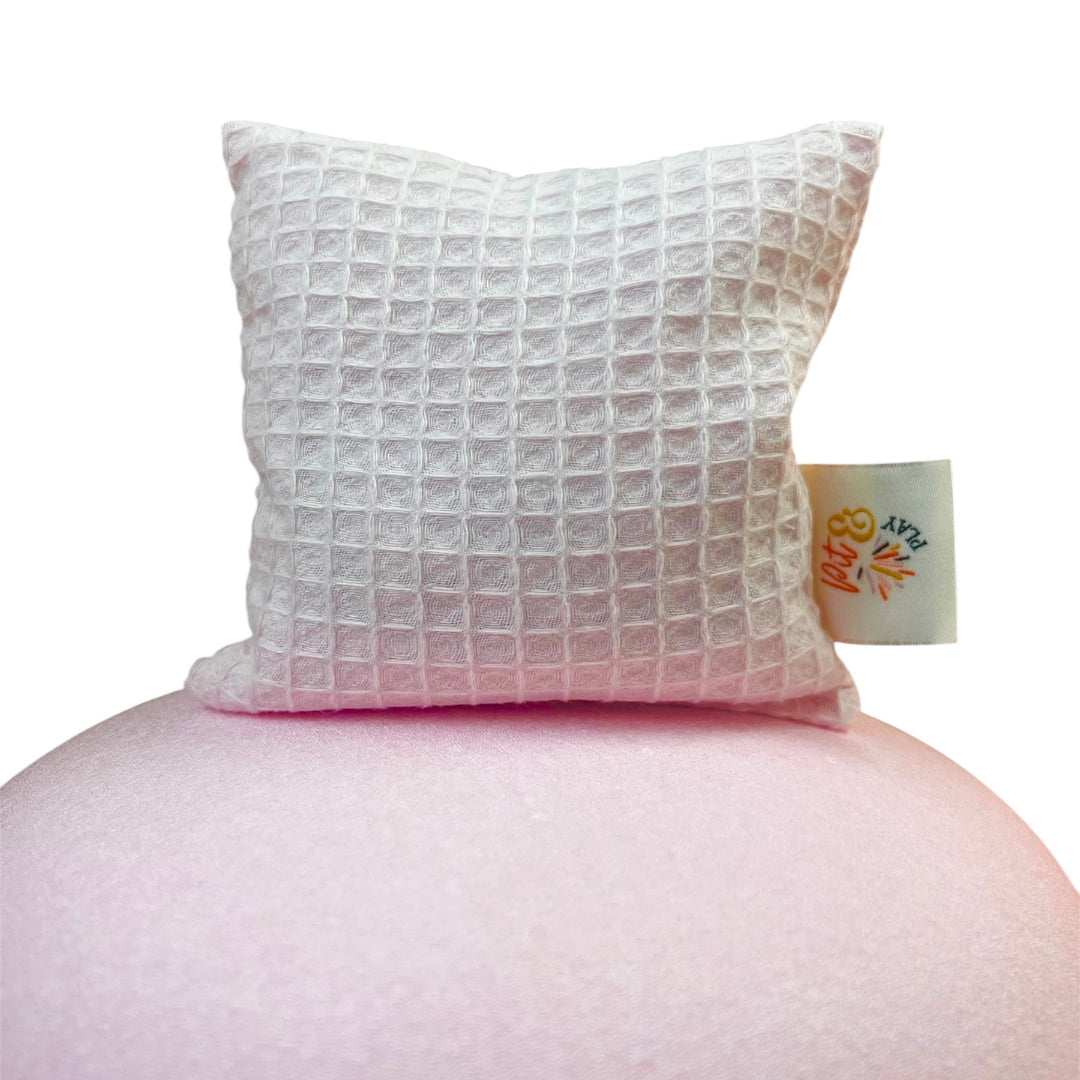 Pit & Play roze pittenzakje met wafeltextuur, staand op een roze ronde ondergrond.