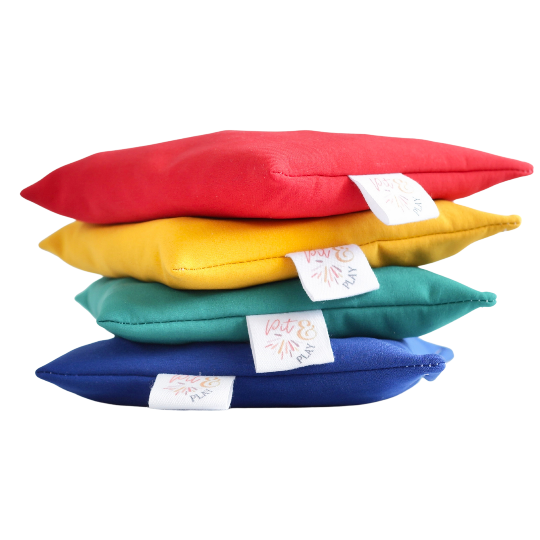 Vier gestapelde pit & play waterafstotende pittenzakken in de kleuren rood, geel, teal en blauw.