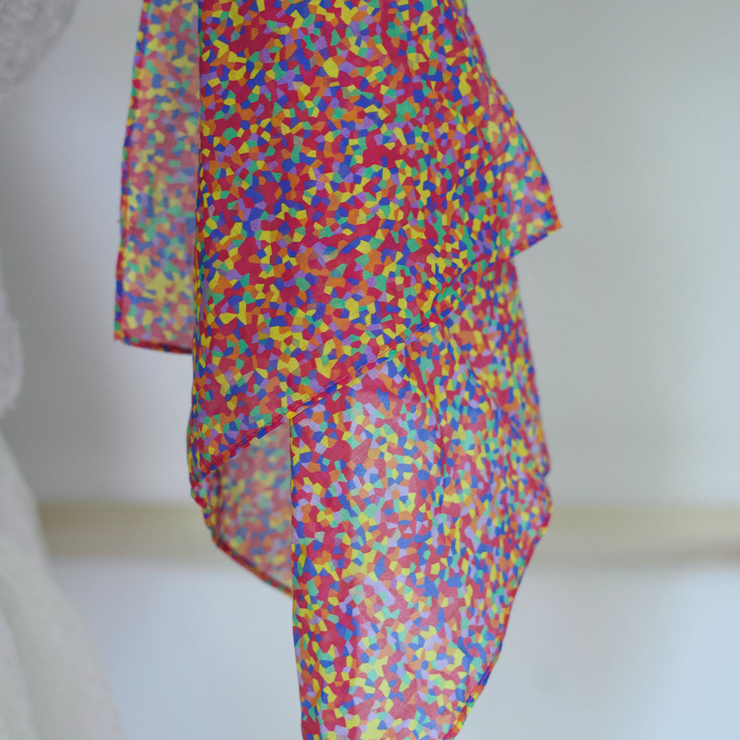 Een pit and play speeldoek met kleurrijk confetti patroon hangt losjes.