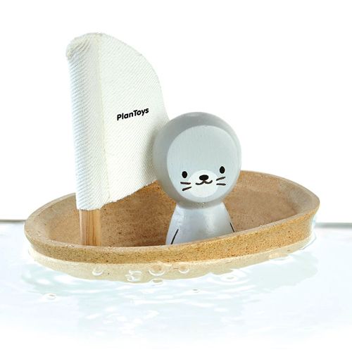 Plan Toys badspeelgoed zeilbootje met zeehondje drijvend in water.