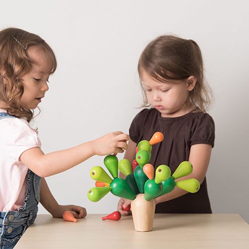Twee kleuters spelen met het Plan Toys houten balanceerspel cactus aan een tafel.