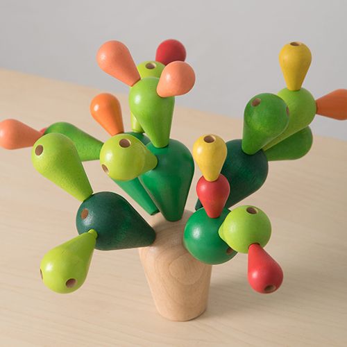 Detail van het Plan Toys houten balanceerspel cactus met groene, oranje, gele en rode onderdelen op een houten ondergrond.