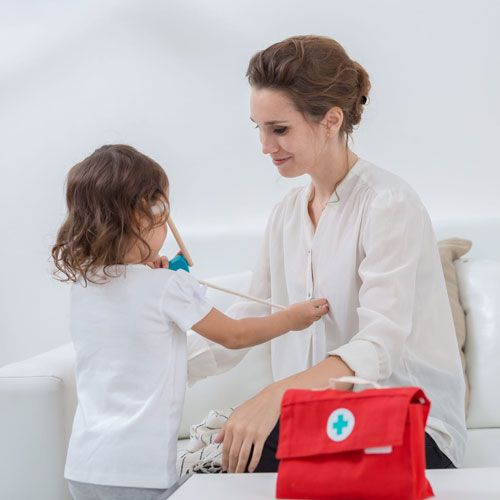 Een kind speelt dokter en onderzoekt een volwassene met de Plan Toys dokterspeelset.
