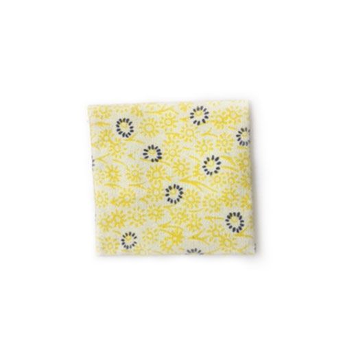 Detail van een geel stoffen poppenhuiskussen met een blauw en geel bloemenpatroon.