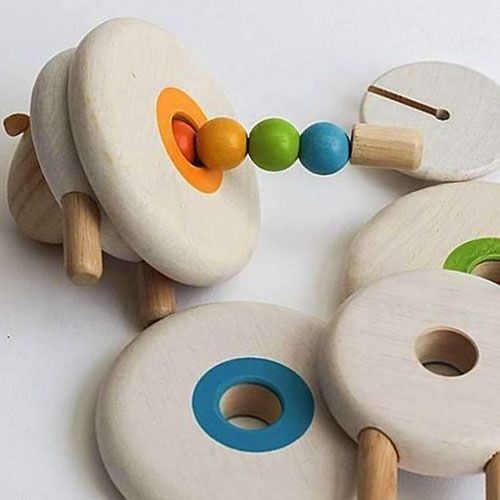 Detail van het houten stapelfiguur schaap, deels uit elkaar gehaald, met gekleurde kralen en ringen.
