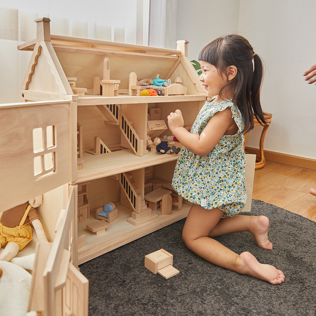 Kind speelt met het Plan Toys Victoriaans houten poppenhuis met meubels.