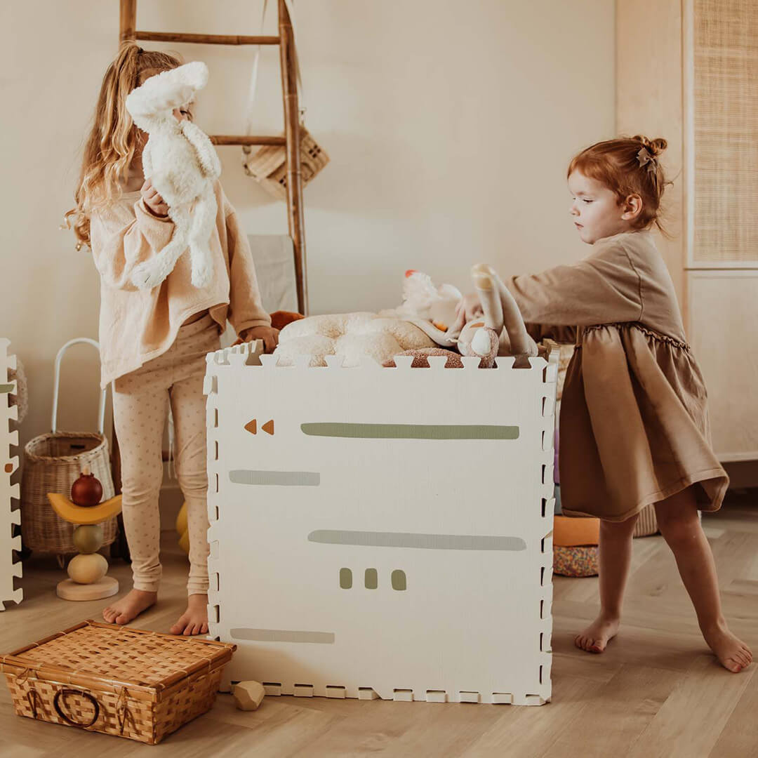Twee kinderen staan naast de play&go foam speelmat die is omgevormd tot een speelgoedopbergbox.