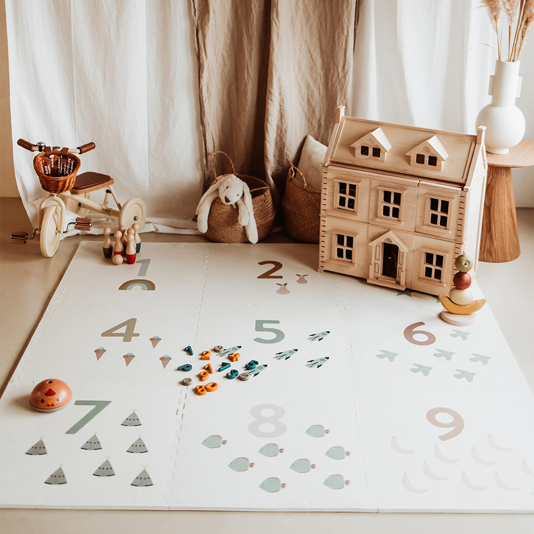 Een play&go foam speelmat met cijfers en illustraties ligt op de grond in een kinderkamer met speelgoed.