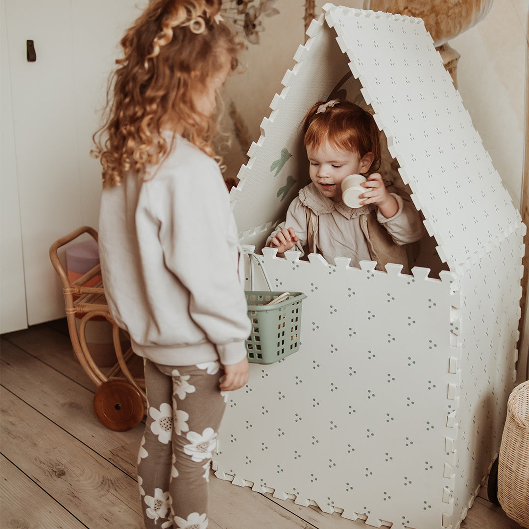 Twee kinderen spelen met de play&go foam speelmat die is opgebouwd als een speelhuisje met stippenpatroon.