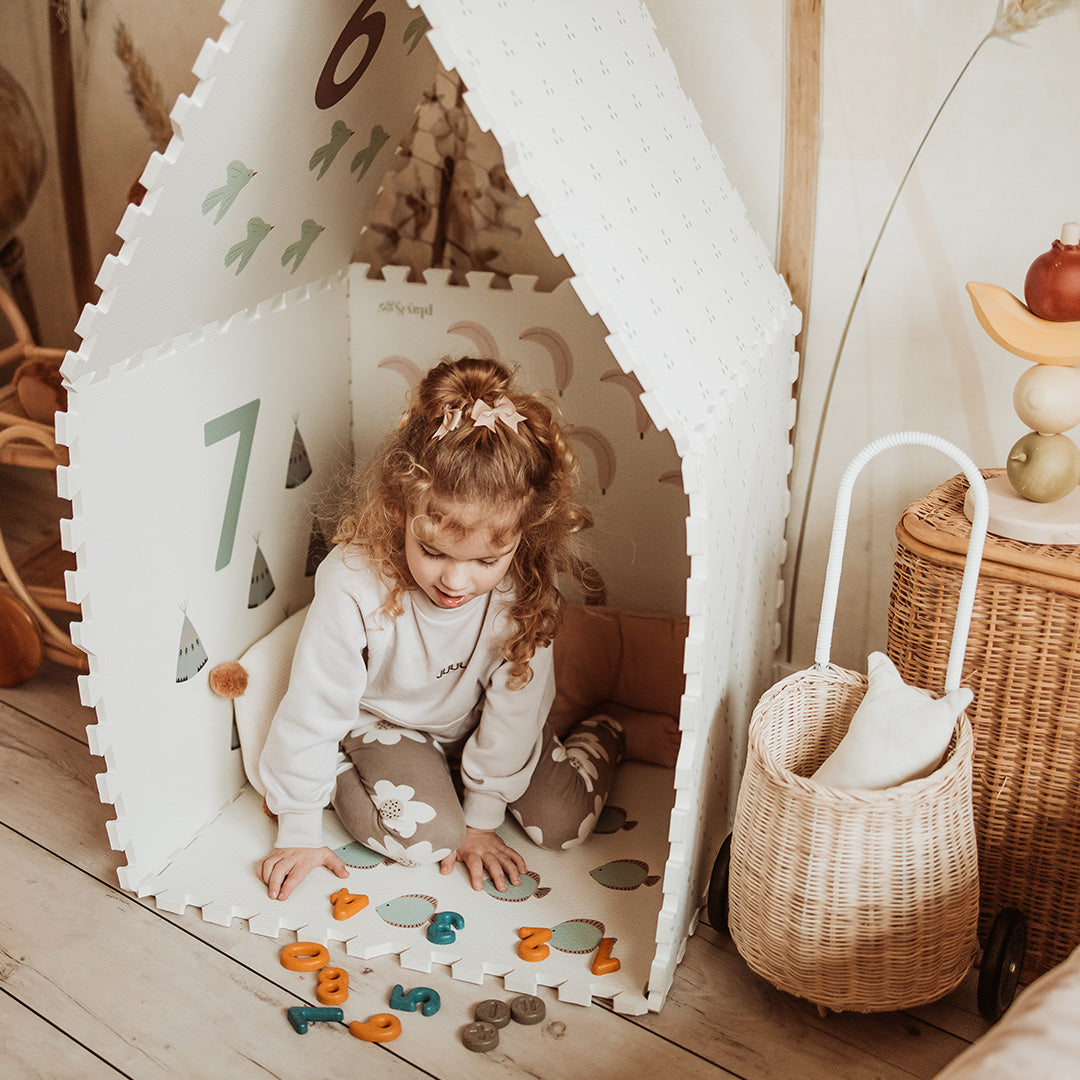 Een kind speelt in een play&go foam speelmat die is opgebouwd als een speelhuisje met cijfers en illustraties aan de binnenkant.