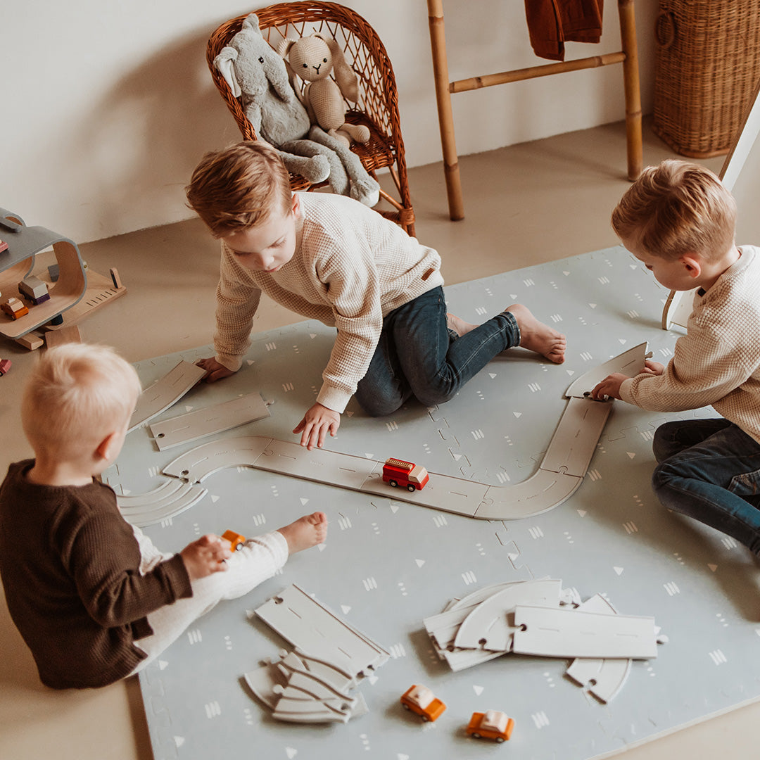 Drie kinderen spelen op de play&go foam speelmat met wegenpatroon en speelgoedauto's.