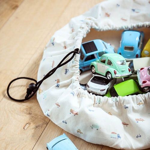 play&go opbergzak met autopatroon, open en gevuld met diverse speelgoedauto's op een houten vloer.