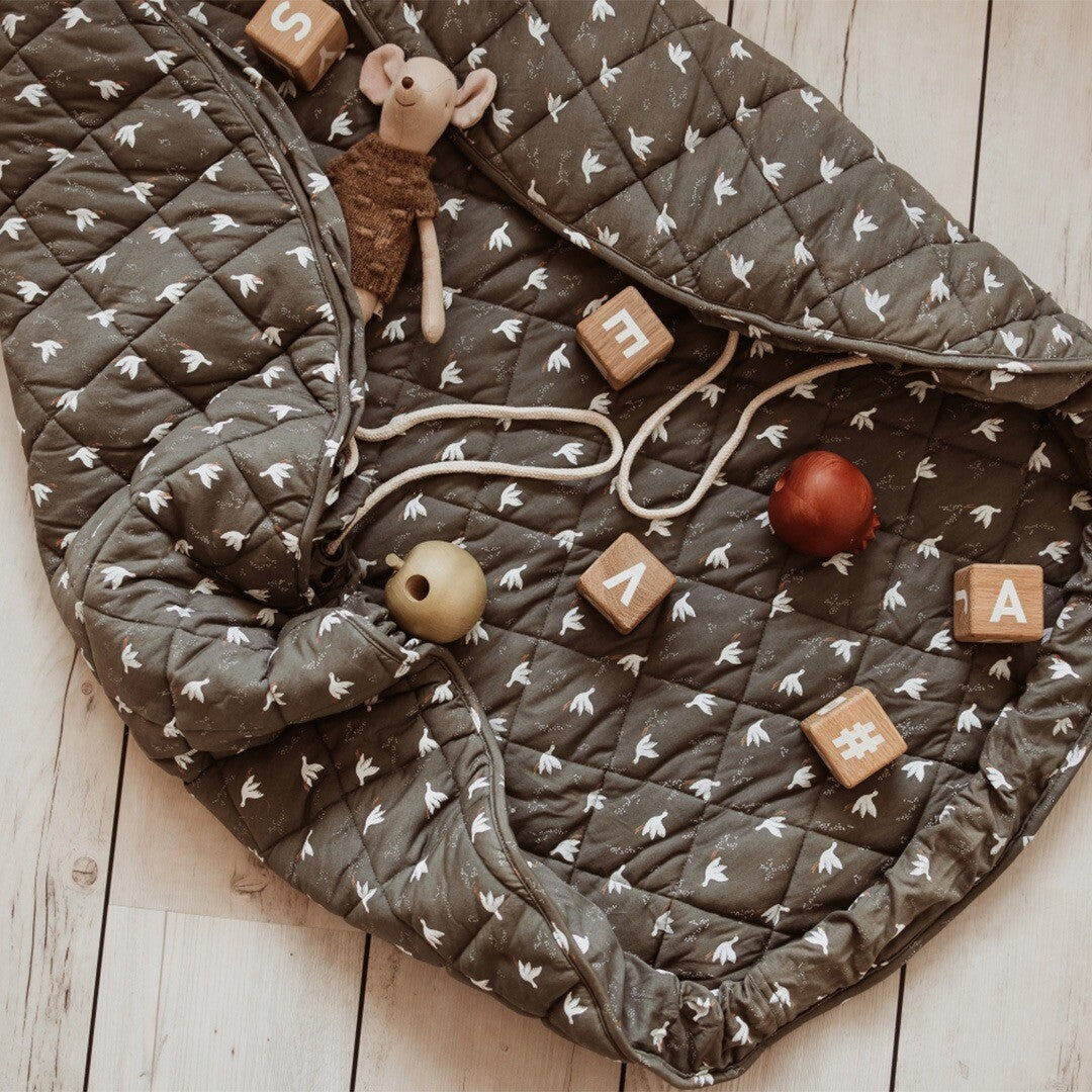 play&go speelkleed met vogelpatroon deels dichtgetrokken als draagtas met speelgoed erin.